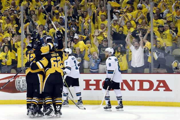 Pittsburgh Penguins' Ben Lovejoy (12) and Carl Hagelin (62) swarm Nick Bonino after his game-winning goal against the San Jose Sharks during the third period in Game 1 of the Stanley Cup final series Monday, May 30, 2016, in Pittsburgh. (AP Photo/Keith Srakocic)