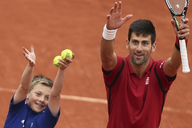 Serbia's Novak Djokovic celebrates with a ball boy after winning the quarterfinal match of the French Open tennis tournament against Tomas Berdych of the Czech Republic in three sets, 6-3, 7-5, 6-3, at the Roland Garros stadium in Paris, France, Thursday, June 2, 2016. (AP Photo/David Vincent)