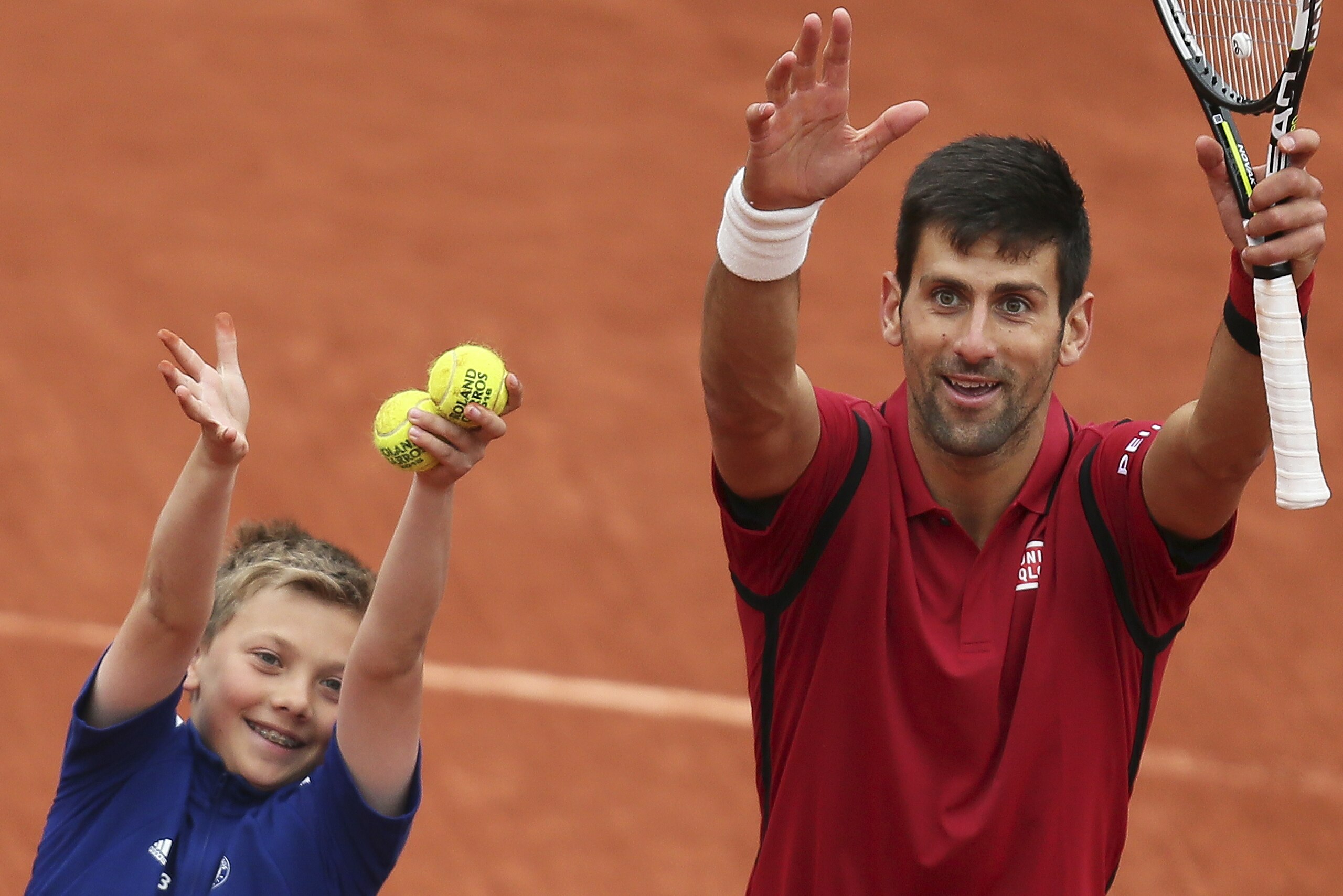 Serbia's Novak Djokovic celebrates with a ball boy after winning the quarterfinal match of the French Open tennis tournament against Tomas Berdych of the Czech Republic in three sets, 6-3, 7-5, 6-3, at the Roland Garros stadium in Paris, France, Thursday, June 2, 2016. (AP Photo/David Vincent)