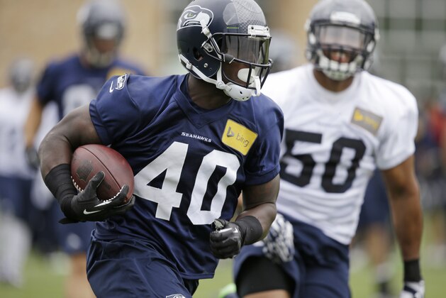 Seattle Seahawks' Derrick Coleman (40) runs with the ball in front of K.J. Wright at a football minicamp practice Tuesday, June 17, 2014, in Renton, Wash. (AP Photo/Elaine Thompson)
