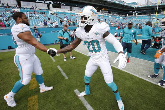 Miami Dolphins strong safety Reshad Jones (20) greets Miami Dolphins defensive tackle Ndamukong Suh (93) as he enter the field before an NFL football game against the Baltimore Ravens, Sunday, Dec. 6, 2015, in Miami Gardens, Fla.  (AP Photo/Wilfredo Lee)