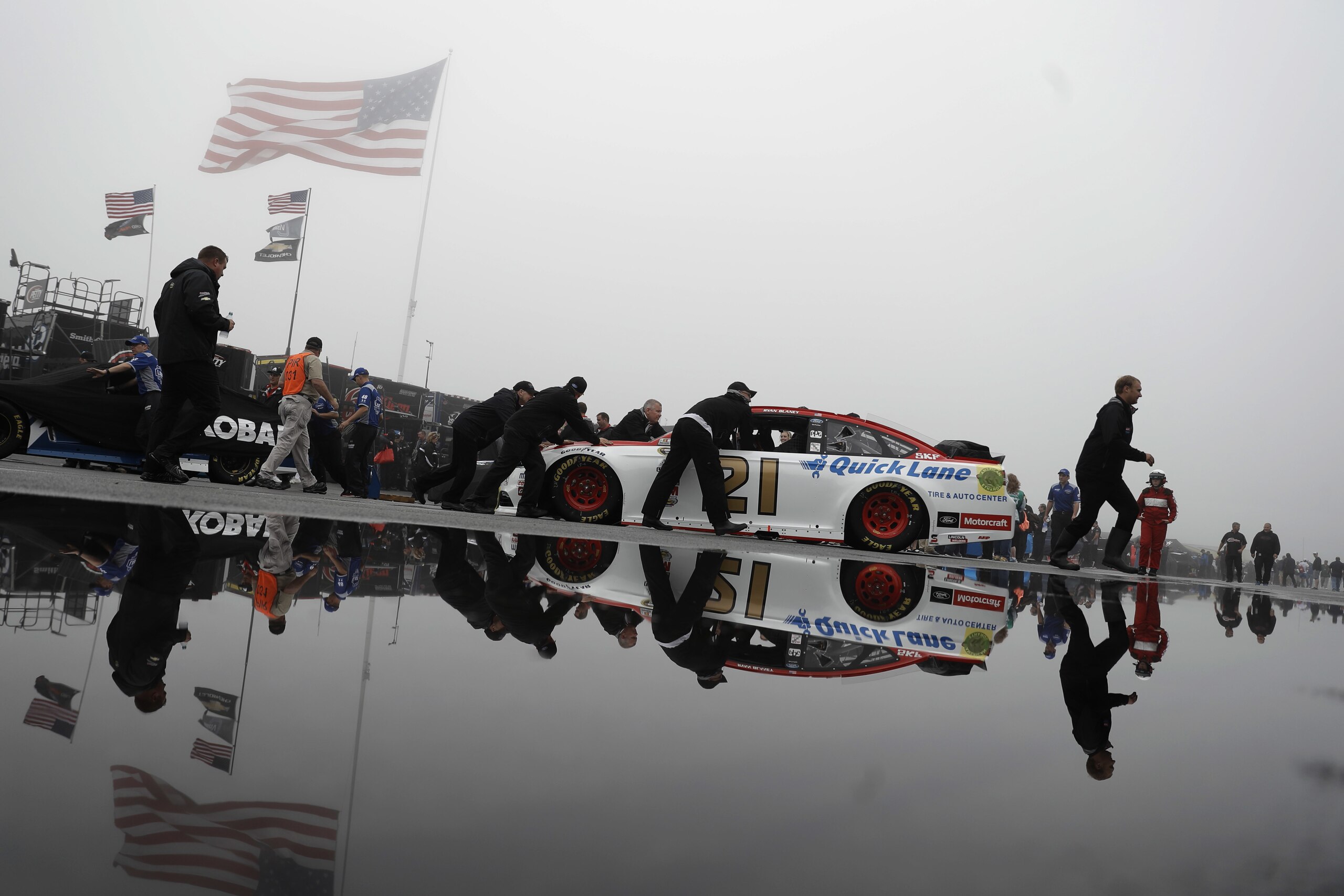 Crew members push the car of Ryan Blaney to the garage before the NASCAR Sprint Cup series auto race, Sunday, June 5, 2016, in Long Pond, Pa. (AP Photo/Matt Slocum)