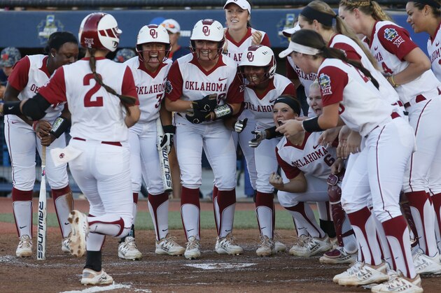 Oklahoma's Sydney Romero (2) is greeted at home plate by her teammates after hitting a home run against Auburn in the third inning of the first game of the best of the best of three  championship series during an NCAA college softball game in the NCAA Women's College World Series in Oklahoma City, Monday, June 6, 2016. (AP Photo/Sue Ogrocki)