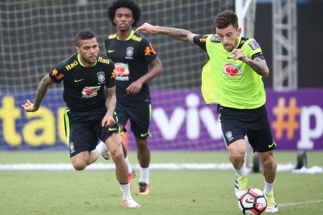 Brazilian midfielder Lucas Lima (R) slips past defender Dani Alves (L) and midfielder Willian during their training session at the University of Central Florida, in Orlando, on June 6, 2016. Brazil will face Haiti on June 7 in their second match of the Copa America Centenario. / AFP / Gregg NEWTON        (Photo credit should read GREGG NEWTON/AFP/Getty Images)