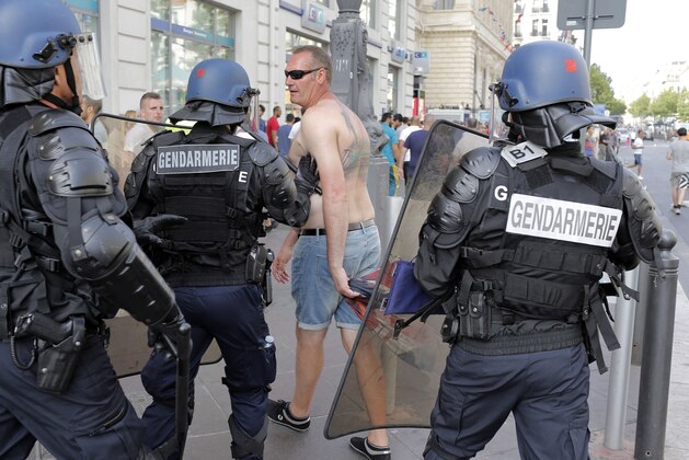 French riot police officers move along an England supporter in downtown Marseille, France, Saturday, June 11, 2016. Riot police have thrown tear gas canisters at soccer fans Saturday in Marseille's Old Port in a third straight day of violence in the city. (AP Photo/Laurent Cipriani)