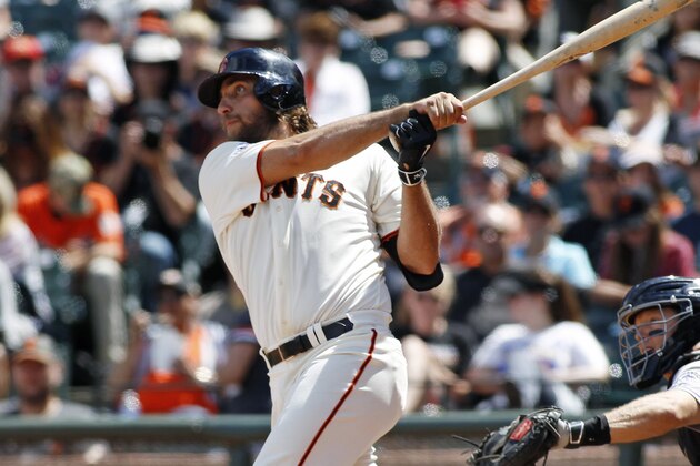 San Francisco Giants' Madison Bumgarner, left, hits a home run against the Colorado Rockies during the seventh inning of a baseball game, Sunday, June 28, 2015, in San Francisco.  Rockies catcher Nick Hundley, right, looks on. (AP Photo/George Nikitin)