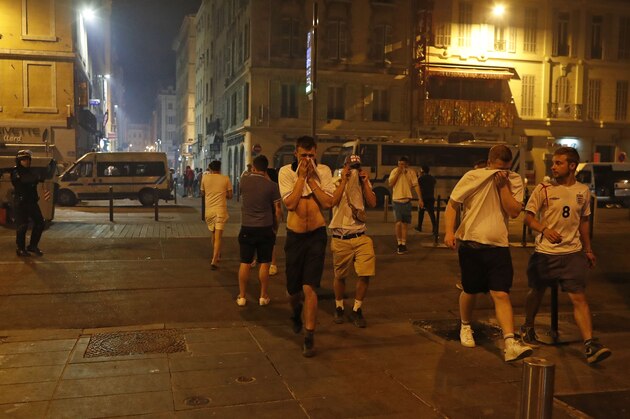 England supporters cover their faces after police fired tear gas following clashes after the Euro 2016 soccer championship group B match between England and Russia in Marseille, France Saturday, June 11, 2016. Clashes between soccer fans Saturday in Marseille's Old Port occurred for a third straight day of violence in the city. (AP Photo/Darko Bandic)