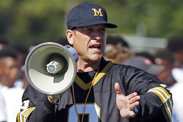 Michigan football coach Jim Harbaugh encourages the more than 500 high school football players in their speed drill, Wednesday, June 8, 2016 at a Michigan Satellite Camp at Pearl High School in Pearl, Miss. Satellite camps continue to be a controversial issue in college football with one side believing they are a great way to generate opportunities for high school prospects and the other side that believes they must be better regulated so coaches do not gain an edge in recruiting. (AP Photo/Rogelio V. Solis)