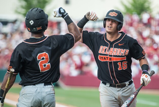 Oklahoma State catcher Collin Theroux (16) celebrates his ninth inning home run with teammate J.R. Davis (2) during an NCAA college baseball tournament super regional game against South Carolina, Saturday, June 11, 2016, in Columbia, S.C. Oklahoma State defeated South Carolina 5-1. (AP Photo/Sean Rayford)