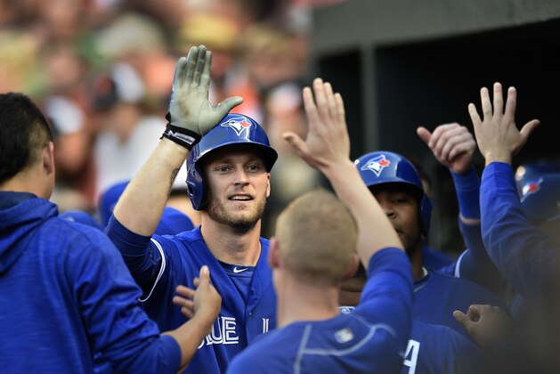 Michael Saunders, de los Azulejos de Toronto, al centro, es felicitado por sus compañeros luego de pegar un jonrón de tres carreras en la primera entrada del juego ante los Orioles de Baltimore el viernes 17 de junio de 2016 en Baltimore. (AP Foto/Gail Burton)