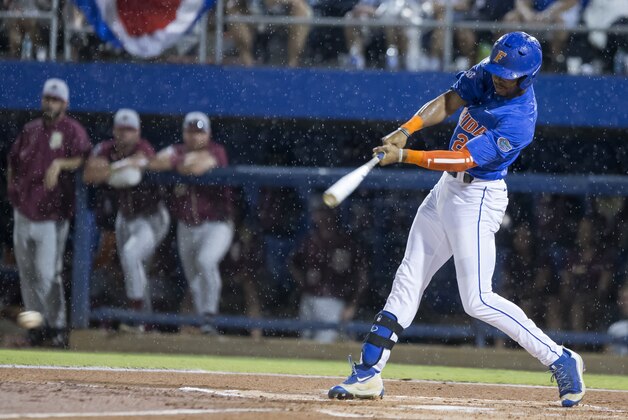 Florida's Buddy Reed (23) hits a ground ball in the rain against Florida State in Game 3 of NCAA college baseball tournament super regional in Gainesville, Fla., on Monday, June 13, 2016.  Florida won 7-0. (AP Photo/Ronald Irby)