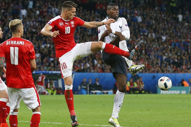 France's Paul Pogba, right, challenges for the ball with Switzerland's Granit Xhaka, center, during the Euro 2016 Group A soccer match between Switzerland and France at the Pierre Mauroy stadium in Villeneuve d’Ascq, near Lille, France, Sunday, June 19, 2016. (AP Photo/Darko Vojinovic)