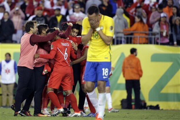 The Peru team celebrates their 1-0 victory as Brazil's Renato Augusto (18) leaves the pitch after a Copa America Group B soccer match between Brazil and Peru Sunday, June 12, 2016, in Foxborough, Mass. (AP Photo/Steven Senne)