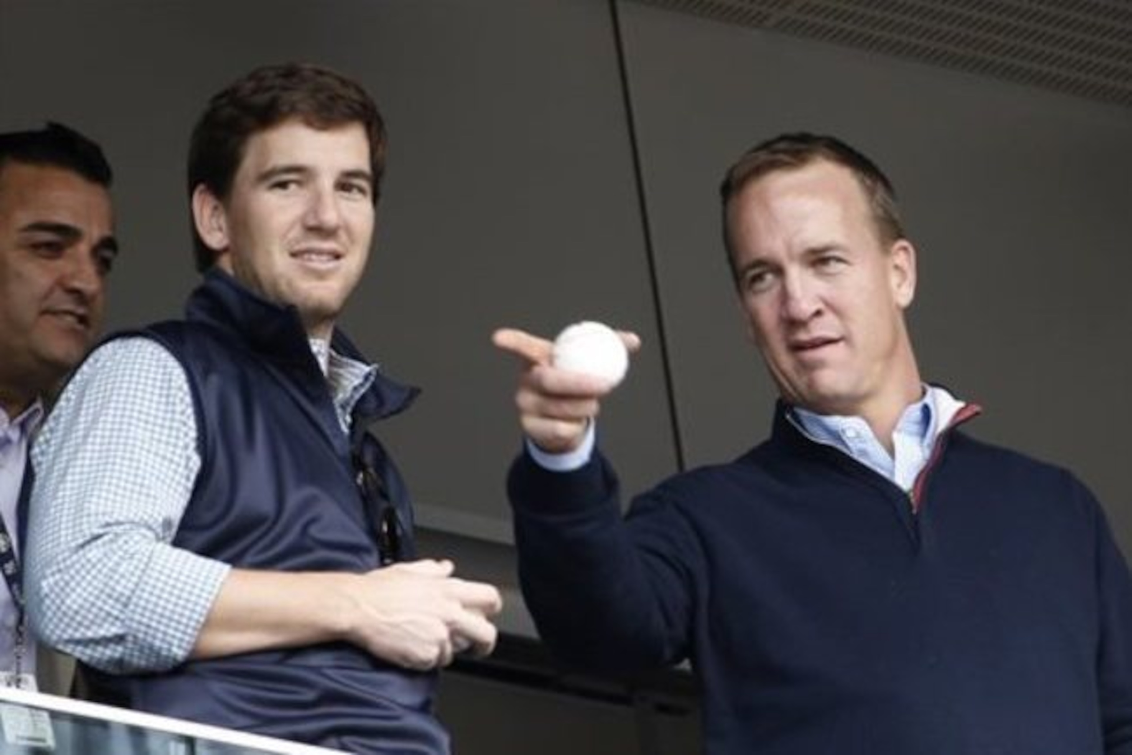 FILE - In this May 4, 2014, file photo, Denver Broncos quarterback Peyton Manning, right, points out something in the stadium to his brother, New York Giants quarterback Eli Manning, from New York Yankees' Derek Jeter's suite during a baseball game between the Yankees and the Tampa Bay Rays at Yankee Stadium in New York. Peyton Manning had a little fun with little brother Eli's sad face at the Super Bowl during an appearance on NBC's