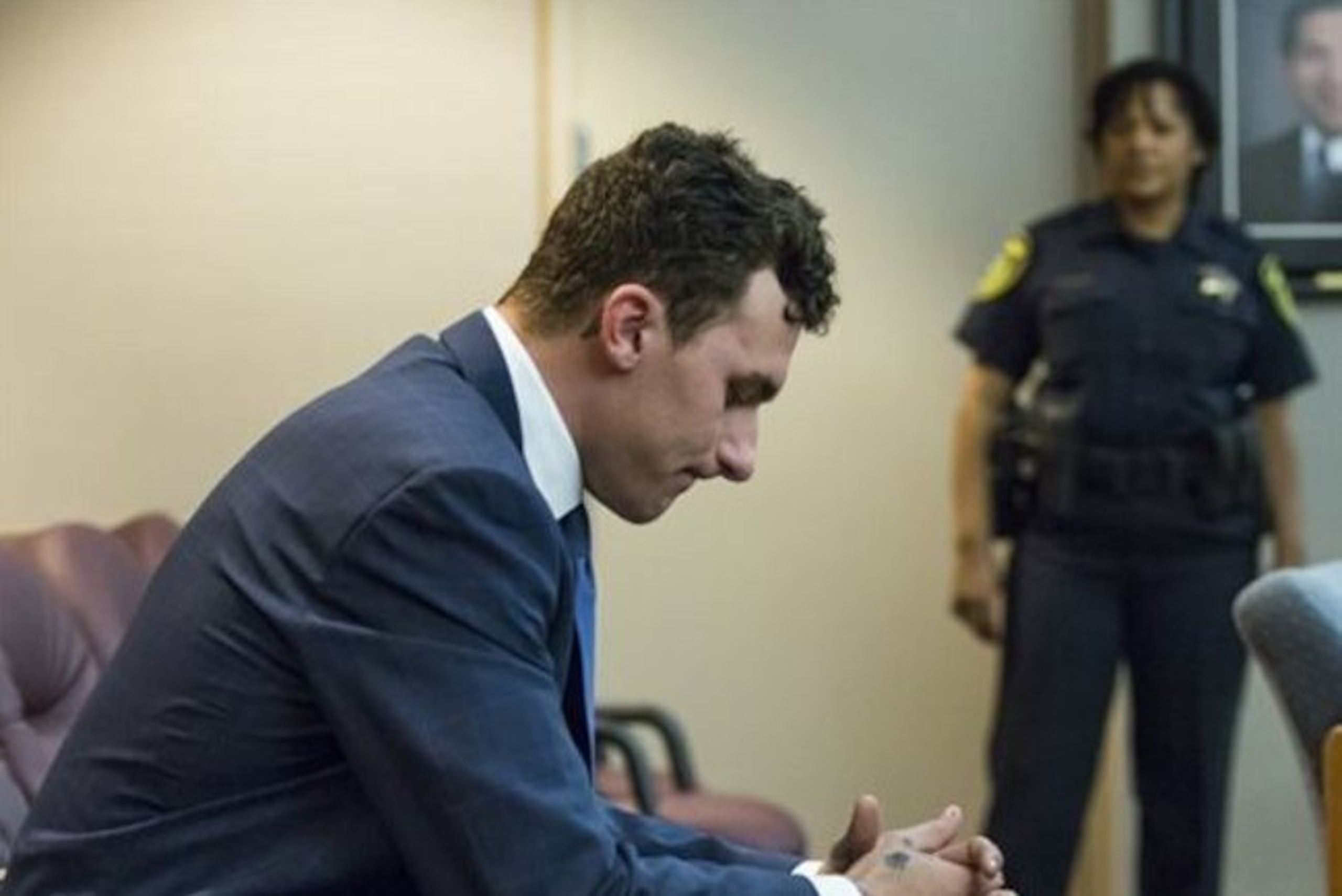 Former Cleveland Browns quarterback Johnny Manziel sits at the back of the courtroom while his defense attorneys confer with the prosecution during his initial hearing, Thursday, May 5, 2016, in Dallas. The Heisman Trophy winner and former Texas A&M star was indicted by a grand jury last month after his ex-girlfriend alleged he hit her and threatened to kill her during a night out in January. No plea was entered, but defense attorney Robert Hinton says Manziel plans to plead not guilty. (Smiley N. Pool/The Dallas Morning News via AP, Pool)