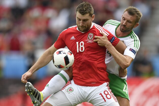 Wales' Sam Vokes, left, challenges for the ball with Northern Ireland's Gareth Mcauley during the Euro 2016 round of 16 soccer match between Wales and Northern Ireland, at the Parc des Princes stadium in Paris, Saturday, June 25, 2016. (AP Photo/Martin Meissner)