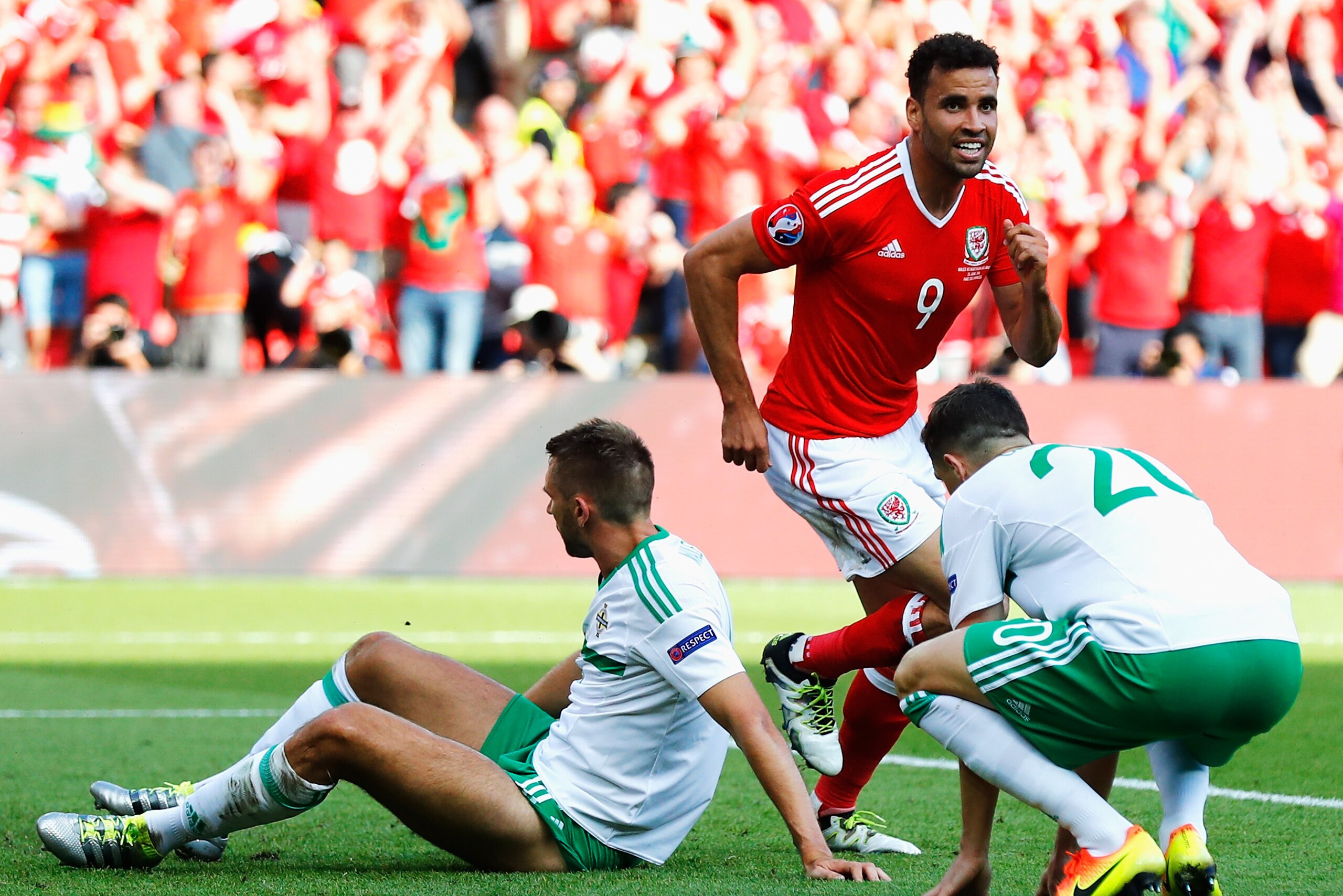 PARIS, FRANCE - JUNE 25:  Hal Robson-Kanu (C) of Wales celebrates his team's first goal while Gareth McAuley (L) of Northern Ireland shows his dejection during the UEFA EURO 2016 round of 16 match between Wales and Northern Ireland at Parc des Princes on June 25, 2016 in Paris, France.  (Photo by Clive Rose/Getty Images)