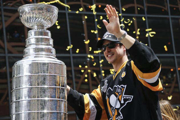 Streamers and confetti fall around Pittsburgh Penguins' Sidney Crosby as he holds onto the Stanley Cup while riding along in the victory parade route in Pittsburgh, Pa., Wednesday, June 15, 2016. The Penguins defeated the San Jose Sharks on Sunday to win the NHL hockey championship. (AP Photo/Keith Srakocic)