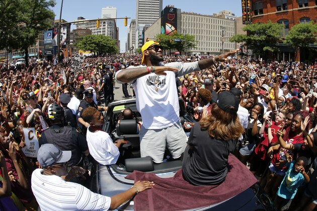 Cleveland Cavaliers' LeBron James, center, stands in the back of a Rolls Royce as it makes it way through the crowd lining the parade route in downtown Cleveland, Wedensday, June 22, 2016, celebrating the Cleveland Cavaliers' NBA Championship. (AP Photo/Gene J. Puskar)