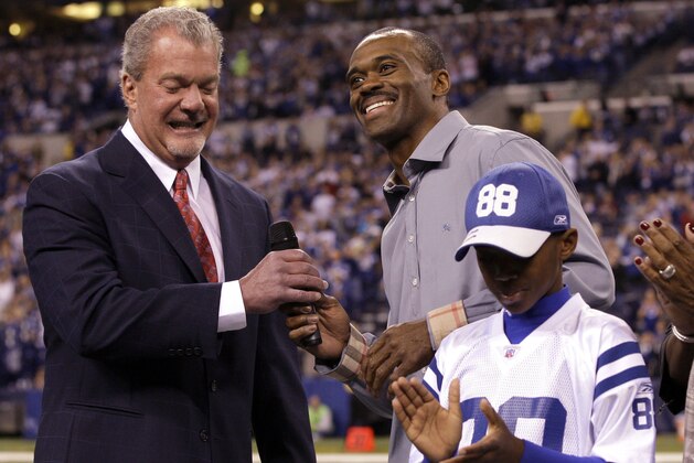 Indianapolis Colts owner Jim Irsay, left, hands a microphone to former wide receiver Marvin Harrison who was inducted into the team's RIng of Honor during half time of an NFL football game against the Carolina Panthers in Indianapolis, Sunday, Nov. 27, 2011. Marvin Harrison Jr., right, applauds. (AP Photo/Darron Cummings)