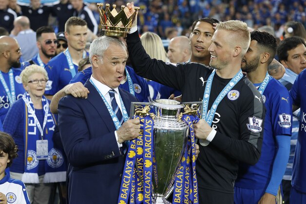 Leicester’s team manager Claudio Ranieri gets a crown by Leicester’s goalkeeper Kasper Schmeichel  as they lift the trophy as Leicester City celebrate becoming the English Premier League soccer champions at King Power stadium in Leicester, England, Saturday, May 7, 2016.(AP Photo/Matt Dunham)