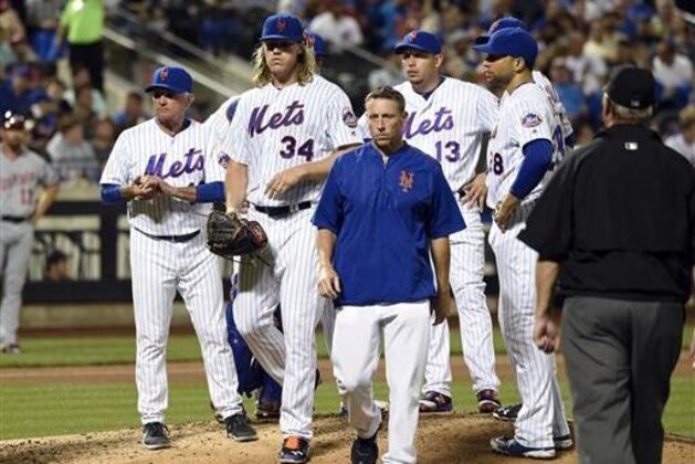 New York Mets manager Terry Collins, left, looks to the dugout as a trainer escorts starting pitcher Noah Syndergaard (34) from the mound in the fifth inning of a baseball game against the Washington Nationals, Friday, July 8, 2016, in New York. (AP Photo/Kathy Kmonicek)