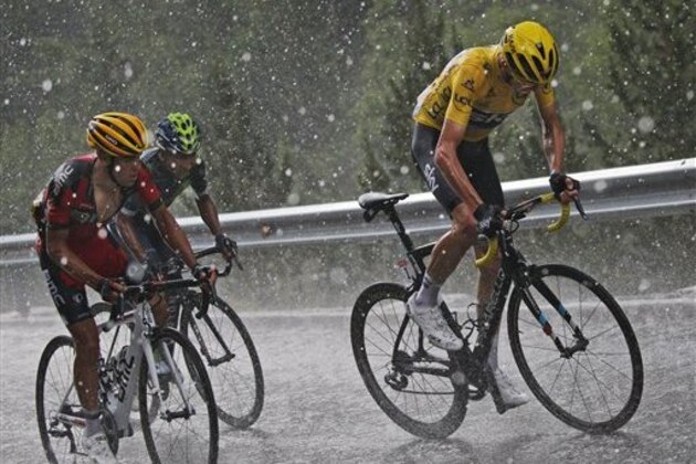 Britain's Chris Froome, wearing the overall leader's yellow jersey, Australia’s Richie Porte, left, and Colombia’s Nairo Quintana, second left, climb in pouring rain and hail  towards Andorra Arcalis during the ninth stage of the Tour de France cycling race over 184.5 kilometers (114.3 miles) with start in Vielha Val d'Aran, Spain, and finish in Andorra Arcalis, Andorra, Sunday, July 10, 2016. (AP Photo/Christophe Ena)