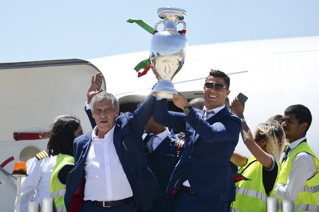 TOPSHOT - Portugal's head coach Fernando Santos (L) and Portugal's forward Cristiano Ronaldo (R) hold the trophy on arrival at Lisbon airport on July 11, 2016 after their Euro 2016 final football win over France yesterday.
The Portuguese football team led by Cristiano Ronaldo returned home to a heroes' welcome today after their upset 1-0 win triumph over France in the Euro 2016 final.

 / AFP / PATRICIA DE MELO MOREIRA        (Photo credit should read PATRICIA DE MELO MOREIRA/AFP/Getty Images)