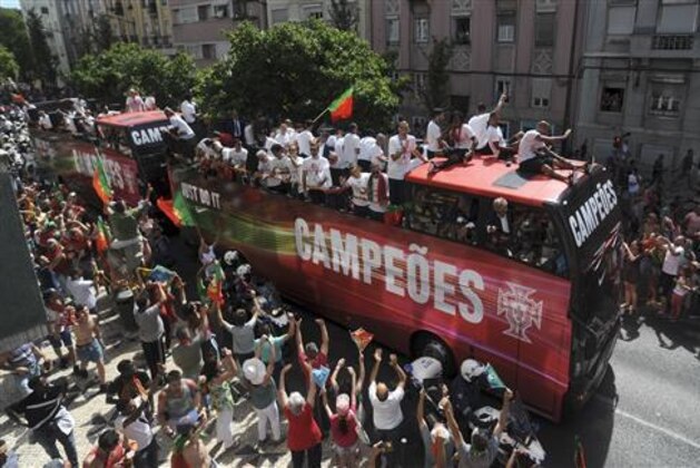 Portugal's soccer team with the Euro 2016 trophy take part in a bus parade in Lisbon, Portugal, Monday, July 11, 2016. Hundreds of thousands of jubilant people lined the sunbaked streets of the Portuguese capital on Monday to greet the national football team after they arrived back from winning the European Championship, its first major trophy.  (AP Photo/Paulo Duarte)