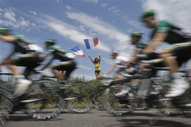 Team Europcar passes a woman waving the French flag on Bastille Day during the 13th stage of the Tour de France cycling race over 217 kilometers (134.8 miles) with start in Saint-Paul-Trois-Chateaux and finish in Le Cap D'Agde, France, Saturday July 14, 2012. (AP PhotoLaurent Cipriani)