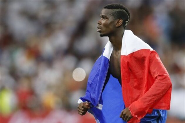 France's Paul Pogba is wrapped in a French flag as he leaves the pitch at the end of the Euro 2016 semifinal soccer match between Germany and France, at the Velodrome stadium in Marseille, France, Thursday, July 7, 2016. France won 2-0. (AP Photo/Frank Augstein)