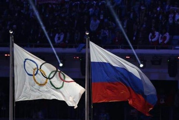 FILE - In this Feb. 23, 2014 file photo the Russian national flag, right, flies after it is hoisted next to the Olympic flag during the closing ceremony of the 2014 Winter Olympics in Sochi, Russia.  On Monday, July 18, 2016 a report on Russian doping by investigator Richard McLaren is to be released in Toronto.  (AP Photo/Matthias Schrader, file)