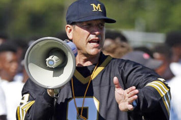 Michigan football coach Jim Harbaugh encourages the more than 500 high school football players in their speed drill, Wednesday, June 8, 2016 at a Michigan Satellite Camp at Pearl High School in Pearl, Miss. Satellite camps continue to be a controversial issue in college football with one side believing they are a great way to generate opportunities for high school prospects and the other side that believes they must be better regulated so coaches do not gain an edge in recruiting. (AP Photo/Rogelio V. Solis)