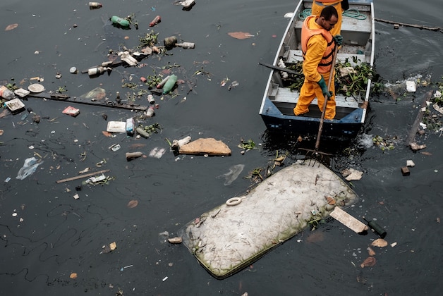 Environment Institute of Rio de Janeiro State (INEA) staffers collect a bed mattress as the tide moves away from the 'eco-barrier' set up to catch floating debris before they enter Guanabara Bay at the mouth of the Meriti river, in Duque de Caxias, next to Rio de Janeiro, Brazil, on July 20, 2016.  / AFP / YASUYOSHI CHIBA        (Photo credit should read YASUYOSHI CHIBA/AFP/Getty Images)