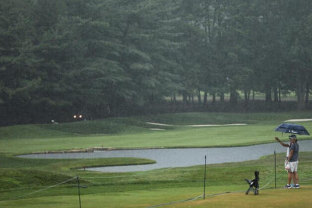 A couple look over the 18th fairway during a weather delay in the third round of the PGA Championship golf tournament at Baltusrol Golf Club in Springfield, N.J., Saturday, July 30, 2016. (AP Photo/Seth Wenig)