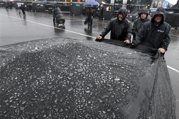 Rain gathers on a car cover as crew members wait in the garage area at Pocono Raceway before the NASCAR Sprint Cup Series Pennsylvania 400 auto race Sunday, July 31, 2016, in Long Pond, Pa. (AP Photo/Mel Evans)