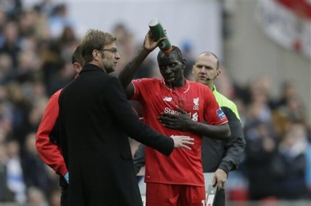 Liverpool's Mamadou Sakho tips a drink over his head as he speaks to his head coach Juergen Klopp before being taken off after a clash of heads with his teammate Emre Can during the English League Cup final soccer match between Liverpool and Manchester City at Wembley stadium in London, Sunday, Feb. 28, 2016. (AP Photo/Tim Ireland)