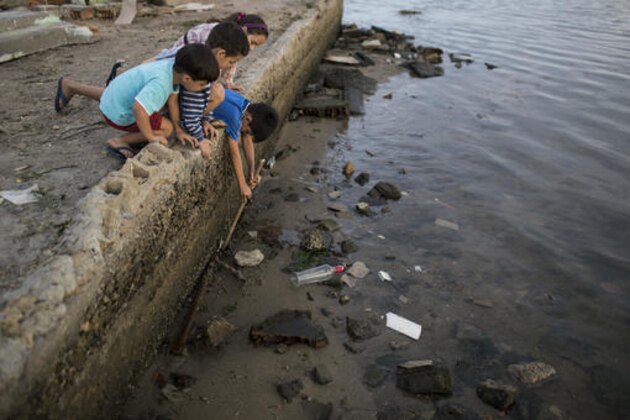 Children try to catch a crab as they play on the polluted shore of Guanabara Bay in Rio de Janeiro, Brazil, Saturday, July 30, 2016. In Rio, the main tourist gateway to the country, a centuries-long sewage problem that was part of Brazil’s colonial legacy has spiked in recent decades in tandem with the rural exodus that saw the metropolitan area nearly double in size since 1970. (AP Photo/Felipe Dana)