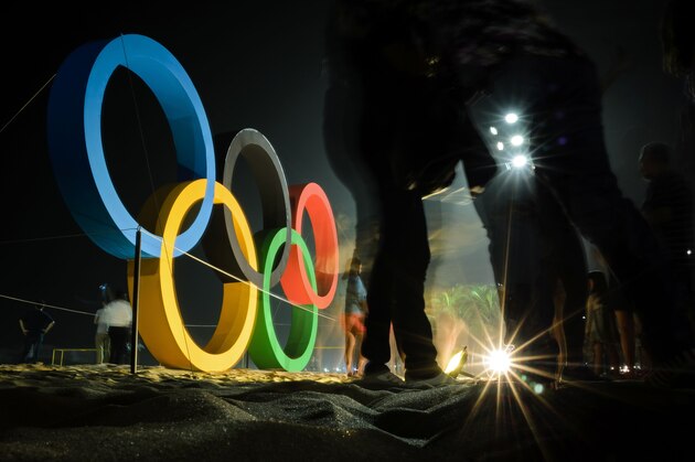 People pose for photographs near to a large Olympic Ring display on Copacabana Beach in Rio de Janeiro on August 1, 2016, ahead of the Rio 2016 Olympic Games. / AFP / LEON NEAL        (Photo credit should read LEON NEAL/AFP/Getty Images)