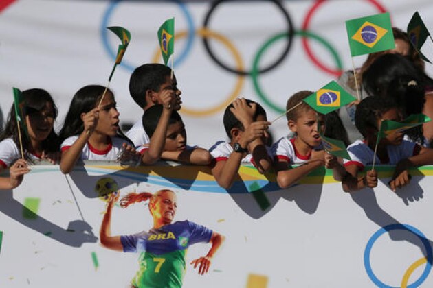 Students wave Brazilian flags during the Olympic torch lighting ceremony at Planalto presidential palace in Brasilia, Brazil, Tuesday, May 3, 2016.  The three-month torch relay across Brazil will end at the opening ceremony on Aug. 5 at Maracana stadium in Rio. (AP Photo/Eraldo Peres)