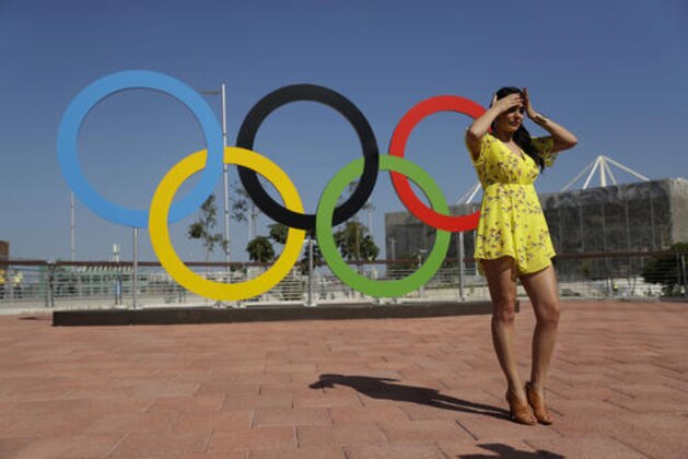 A woman working for a Mexican television program tries to shield from the sun between takes by the Olympics rings in the Olympic Park ahead of the start of the 2016 Summer Olympics in Rio de Janeiro, Brazil, Monday, Aug. 1, 2016. (AP Photo/Matt Dunham)