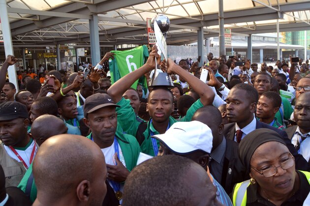 Nigeria's Kelechi Nwakali (C) carries the Fifa Under-17 World Cup trophy on his head in the midst of a crowd gathered to receive the triumphant Nigeria U17 team, the Golden Eaglets, at Nnamdi Azikiwe Airport in Abuja, on November 11, 2015. Nigeria's Golden Eaglets emerged champions of the Fifa Under-17 World Cup in Chile after defeating Mali 2-0. AFP PHOTO / STRINGER        (Photo credit should read -/AFP/Getty Images)