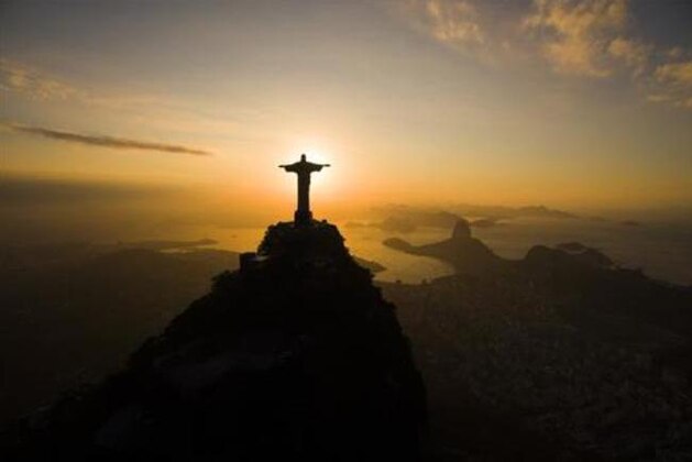 The sun rises behind the Christ the Redeemer statue, above the Guanabara bay in Rio de Janeiro, Brazil, Tuesday, July 19, 2016. With the Olympics set to start on Aug. 5, the games and the city have been overshadowed by security threats, violence, the Zika virus and a national political corruption scandal. (AP Photo/Felipe Dana)