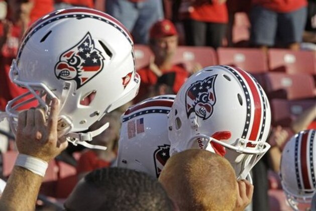 Louisville players hold up their helmets which feature a logo honoring the memory of those individuals killed in the Sept. 11, 2001, terrorist attacks, at an NCAA college football game against Eastern Kentucky at Cardinal Stadium in Louisville, Ky., Saturday, Sept. 11, 2010. (AP Photo/Garry Jones)