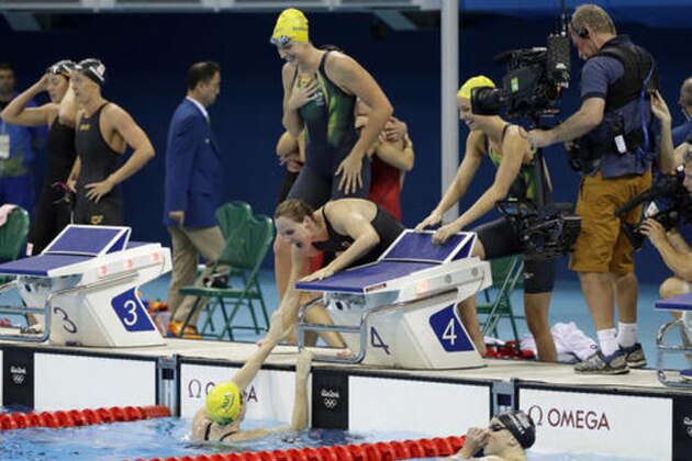 Australia's Cate Campbell, is greeted by teammates after anchoring the team to gold in the women's 4x100-meter freestyle relay as United States' Katie Ledecky looks on during the swimming competitions at the 2016 Summer Olympics, Saturday, Aug. 6, 2016, in Rio de Janeiro, Brazil. (AP Photo/Matt Slocum)