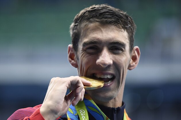TOPSHOT - USA's Michael Phelps kisses his gold medal on the podium after Team USA won the Men's 4x200m Freestyle Relay Final during the swimming event at the Rio 2016 Olympic Games at the Olympic Aquatics Stadium in Rio de Janeiro on August 9, 2016.   / AFP / GABRIEL BOUYS        (Photo credit should read GABRIEL BOUYS/AFP/Getty Images)