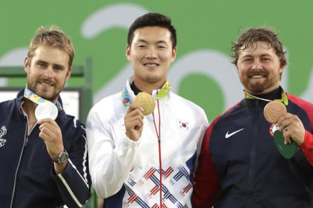 Gold medal winner Ku Bon-chan of South Korea, center, celebrates on the podium with silver medalist Jean Charles Valladont, left, and bronze medalist Brady Ellison of the United States at the awards ceremony of the men's individual archery competition at the Sambadrome venue during the Summer Olympics in Rio de Janeiro, Brazil, Friday, Aug. 12, 2016. (AP Photo/Alessandra Tarantino)