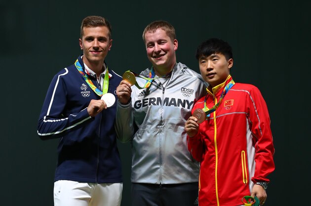 Aug 13, 2016; Rio de Janeiro, Brazil; Christian Reitz (GER) , Jean Quiquampoix (FRA) and Yuehong Li (CHN) on the podium after the men's 25m rapid fire pistol finals in the Rio 2016 Summer Olympic Games at Olympic Shooting Centre. Mandatory Credit: Guy Rhodes-USA TODAY Sports