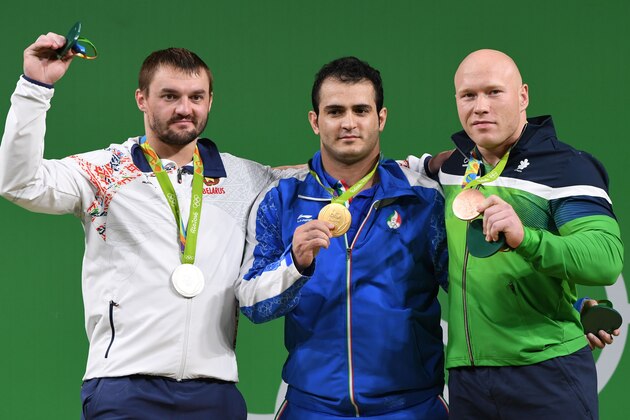 Iran's Sohrab Moradi (C), gold, Belarus' Vadzim Straltsou, silver, and Lithuania's Aurimas Didzbalis, bronze, pose during the podium ceremony of the men's weightlifting 94kg event at the Rio 2016 Olympic Games in Rio de Janeiro on August 13, 2016. / AFP / GOH Chai Hin        (Photo credit should read GOH CHAI HIN/AFP/Getty Images)