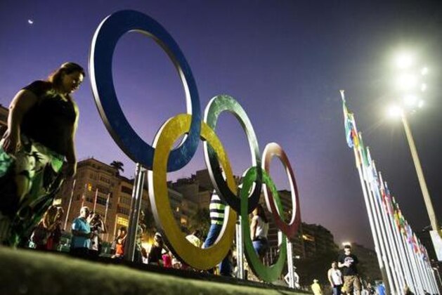 Pedestrians pass by the Olympic rings along Copacabana beach, site of the cycling road race, beach volleyball, marathon swimming and triathlon competitions at the 2016 Summer Olympics, in Rio de Janeiro, Brazil, Saturday, Aug. 6, 2016. (AP Photo/David Goldman)